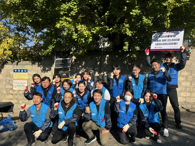 14일 서울 용산구 서부이촌동 인근 주택가에서 사랑의 연탄 나르기 봉사활동에 참여한 SGI서울보증 직원들이 기념사진을 촬영하고 있다. 서울보증 제공.