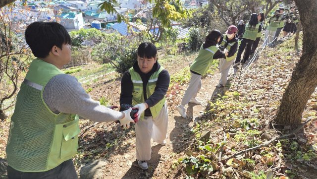 봉사 활동에 함께한 학생들이 길게 줄지어 서서 연탄을 나르고 있다. 통영시새마을회 제공