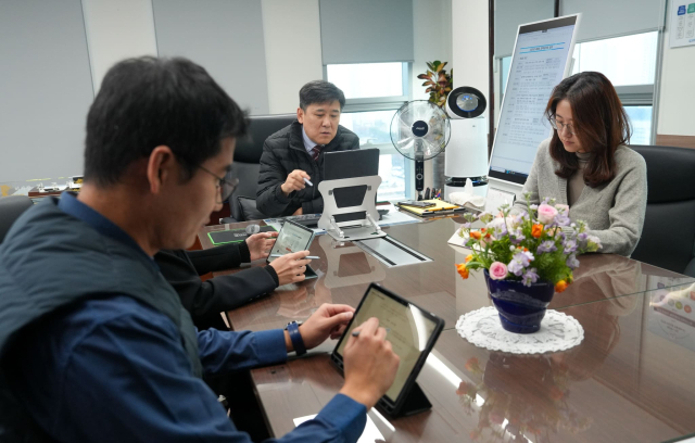 김준석 한국해양교통안전공단(KOMSA) 이사장(가운데)이 세종 본사 집무실에서 기획조정실 직원들과 대형 모니터와 태블릿PC를 활용한 ‘종이 없는 회의’를 진행 중인 모습. KOMSA 제공