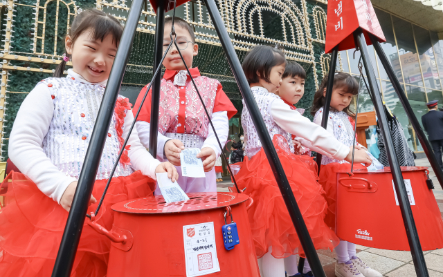 1일 부산 부산진구 롯데백화점 부산본점 앞에서 구세군 자선냄비 시종식이 열려 축하공연을 한 어린이들이 자선냄비에 돈을 넣고 있다. 김종진 기자 kjj1761@