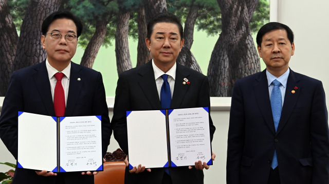 더불어민주당 김병기 원내대표(가운데), 국민의힘 송언석 원내대표(왼쪽), 구윤철 부총리 겸 기획재정부 장관이 2일 국회에서 2026년도 예산안 처리를 위한 합의문에 서명한 뒤 기념 촬영하고 있다. 연합뉴스