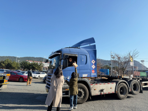 부산항만공사 직원들이 화물차 운전자에게 계절관리제 홍보물품을 전달하고 있다.