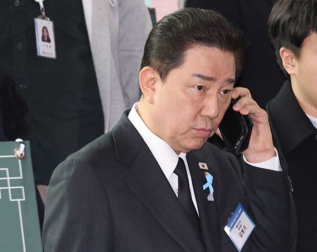 더불어민주당 김병기 원내대표가 29일 전라남도 무안군 무안국제공항 여객터미널에서 열린 12·29 여객기 참사 1주기 추모식을 마친 뒤 이동하며 전화 통화를 하고 있다. 연합뉴스