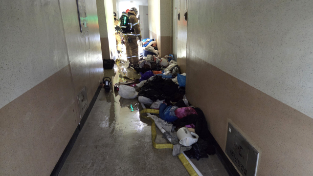 29일 오전 울산 남구 달동의 한 아파트 화재 현장 복도에서 소방대원들이 잔불 정리 등 후속 조치를 하고 있다. 복도 바닥에는 화재 진압에 사용된 물이 흥건하게 고여 있고, 불이 난 세대 내부에서 꺼낸 것으로 보이는 각종 쓰레기와 집기류가 어지럽게 널려 있어 당시 긴박했던 상황과 진화 작업의 어려움을 짐작하게 한다. 울산소방본부 제공