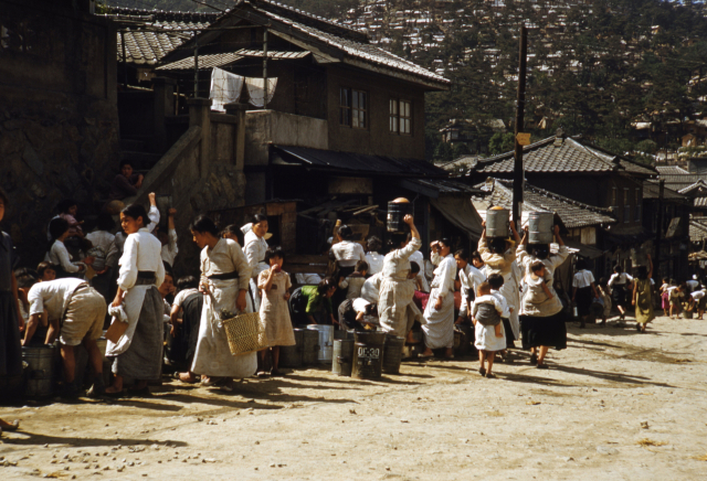 1952년 부산 영주동 길가의 공동수도에서 물을 길어 나르는 주민들 모습. 현재의 코모도호텔 앞 대로변으로 추정된다. 부경근대사료연구소 제공·부산일보DB