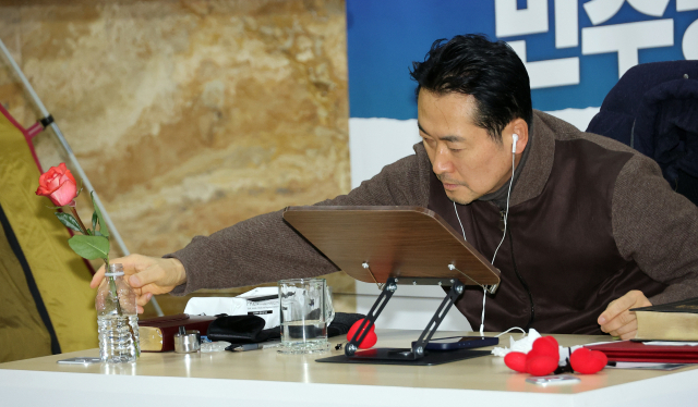 국민의힘 장동혁 대표가 18일 국회 로텐더홀에서 더불어민주당에 통일교·공천헌금 '쌍특검' 수용을 요구하며 나흘째 단식을 이어가던 중 책상 위의 꽃을 다듬고 있다. 연합뉴스