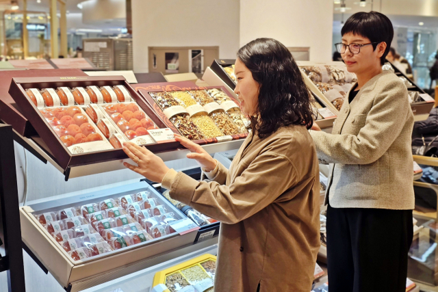 롯데백화점 부산본점 지하 1층 이대명과에서 설날 선물세트 사전 예약 판매를 진행하고 있다. 아래는 신세계백화점 센텀시티 백화점 지하 1층 식품관 사전 예약 행사장에서 설 선물세트를 둘러보는 고객들. 롯데백화점·신세계 센텀시티 제공