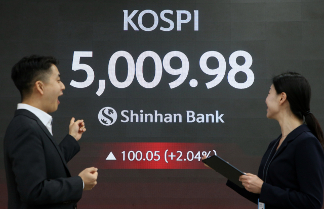 코스피가 장중 5000을 넘긴 22일 서울 신한은행 본점 로비에서 딜러들이 미소 짓고 있다. 연합뉴스