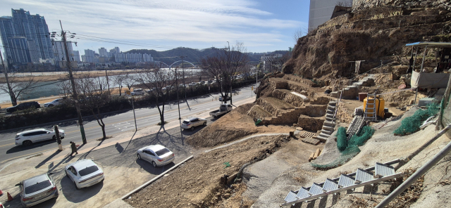 28일 오후 울산 중구 태화강변 언덕 쪽에서 진행된 고지배수터널 공사 현장이 흙과 돌로 되메워진 채 주차장으로 변해 있다. 중구청은 태화동 수해 대책의 일환으로 이 지점부터 태화동행정복지센터까지 390m 가량 지하 배수로를 만들 계획이었으나 면밀하지 못한 사업 추진으로 수십억 원 세금만 날린 채 백지화했다. 권승혁 기자