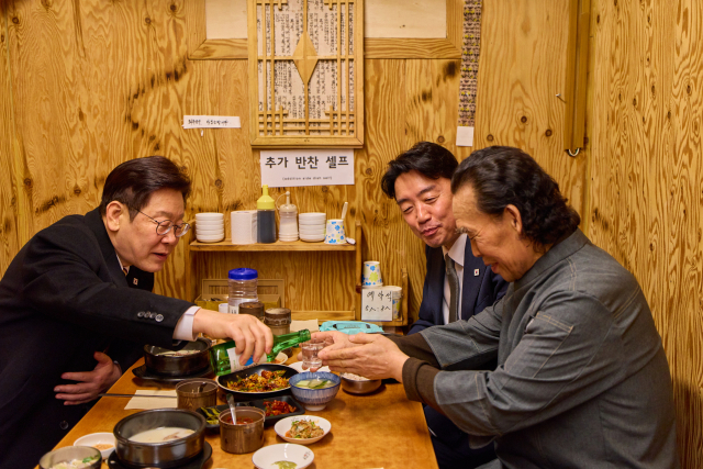이재명 대통령이 9일 서울 종로구 통인시장 한식당에서 강훈식 대통령비서실장과 저녁 식사를 하며 식당 주인에게 술을 권하고 있다. 연합뉴스