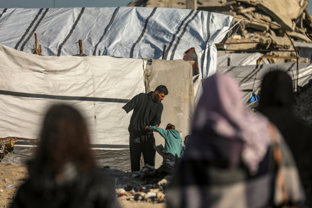 11일(현지 시간) 이스라엘과 하마스 간 휴전이 진행 중인 가자시티 동부의 알 투파 지역에서 절단 수술을 받은 팔레스타인인 아버지가 딸들과 함께 서 있다. EPA연합뉴스