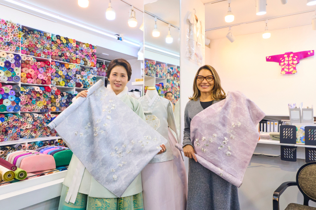 김혜경 여사와 루이스 이나시우 룰라 다시우바 브라질 대통령 부인 호잔젤라 다시우바 여사가 21일 서울 종로구 광장시장의 한 한복가게에서 진행된 친교일정에서 함께 실크원단을 들고 기념촬영을 하고 있다. 연합뉴스