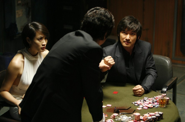 영화 <타짜>의 한 장면. 도박꾼 아귀가 밑장빼기를 의심하고 주인공 고니의 손을 잡고 위협하는 모습이다.