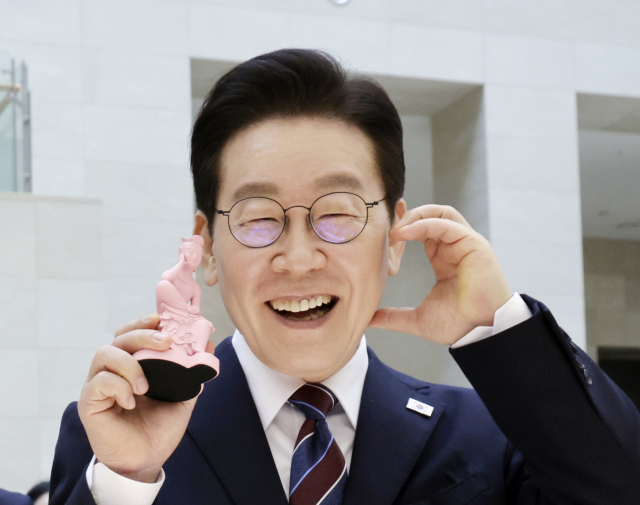 이재명 대통령이 26일 서울 용산구 국립중앙박물관에서 열린 특별전 '우리들의 이순신'을 관람한 뒤 상품관에서 기념품을 들고 포즈를 취하고 있다. 연합뉴스