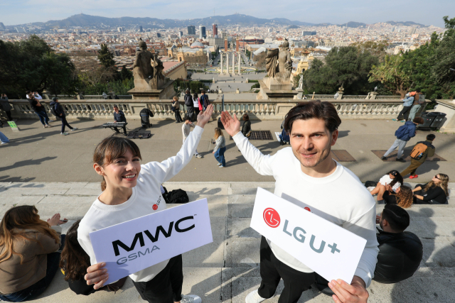 = 27일(현지시간) '모바일 월드 콩그레스(MWC2026)'가 열리는 스페인 바르셀로나에서 LG유플러스 전시 현지 관계자들이 바르셀로나 시내 배경으로 사진 촬영을 하며 행사 개막을 알리고 있다. 연합뉴스