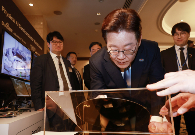 이재명 대통령이 2일 싱가포르의 한 호텔에서 열린 한-싱가포르 AI 커넥트 서밋이 끝난 뒤 한 전시업체가 준비한 웨이퍼에 서명하고 있다. 연합뉴스