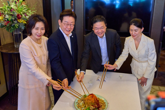 이재명 대통령과 김혜경 여사가 2일 싱가포르 한 호텔에서 로런스 웡 총리 부부와 친교 오찬에 앞서 싱가포르 새해 음식인 생선회 샐러드를 섞으며 덕담을 나누고 있다. 연합뉴스