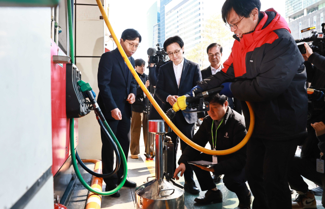 김정관 산업통상부 장관(앞줄 왼쪽 두 번째)이 석유제품 최고가격제 시행 첫날인 13일 서울의 한 주유소를 방문해 한국석유관리원 관계자들이 정량기준탱크를 이용해 유류 정량을 확인하는 모습을 지켜보고 있다. 산업부 제공