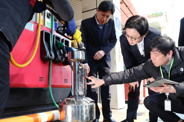 김정관 산업통상부 장관(오른쪽 두 번째)이 석유 최고가격제 시행 첫날인 지난 13일 서울의 한 주유소를 방문해 한국석유관리원 관계자들이 정량기준탱크를 이용해 유류 정량을 확인하는 모습을 지켜보고 있다. 연합뉴스