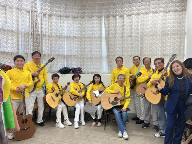 울타리음악단 정명선(오른쪽) 단장이 지도하고 있는 어진샘 노인종합복지관 기타반 수강생들.