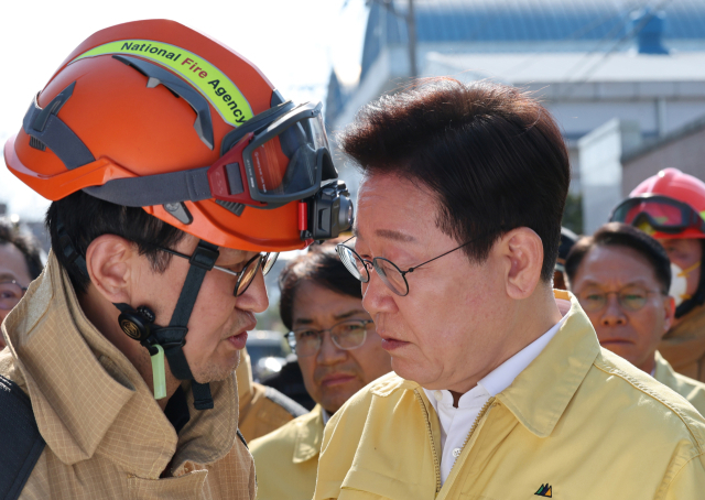 이재명 대통령이 21일 대전 대덕구 안전공업 건물의 대형 화재 현장을 찾아 상황보고를 받고 있다. 연합뉴스