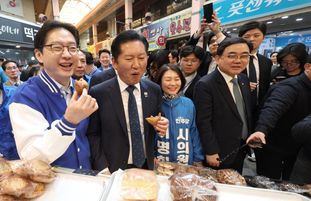 더불어민주당 정청래 대표가 23일 오후 경남 양산시 중부동 양산남부시장에서 찹쌀도넛을 먹고 있다. 왼쪽은 김경수 경남지사 후보. 연합뉴스