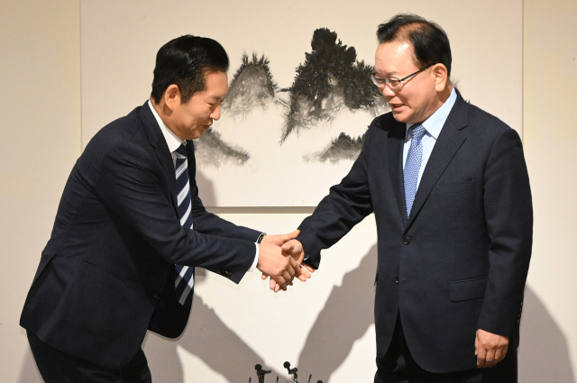 더불어민주당 정청래 대표와 김부겸 전 국무총리가 26일 서울 중구 달개비에서 회동 전 손을 맞잡고 있다. 연합뉴스