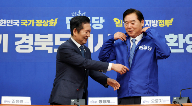 더불어민주당 정청래 대표가 지난 1일 국회에서 열린 오중기 경북도지사 후보 환영식에서 오 후보에게 당 점퍼를 입혀주고 있다. 연합뉴스