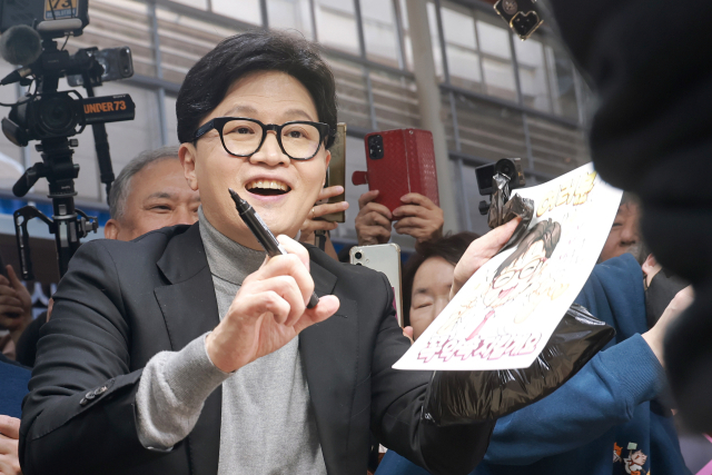 국민의힘 한동훈 전 대표가 22일 서울 동대문구 경동시장을 방문해 상인에게 사인해주고 있다. 연합뉴스