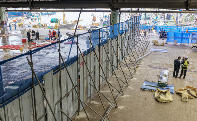 부산공동어시장 현대화 사업으로 본 건물 철거가 시작된 14일 부산 서구 공동어시장에서 1단계 공사 구간인 남항 쪽 1돌제부두에 펜스가 설치돼 위판장 면적이 40%가량 줄어든 채 위판이 진행되고 있다. 김종진 기자 kjj1761@