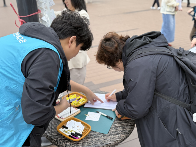 20일 장애인의 날을 맞아 부산 곳곳에서 기념식과 각종 행사가 열린다. 사진은 지난 14일 수영구 일대에서 진행된 장애 인식 개선 캠페인에서 시민들이 장애인들에게 응원 메시지를 적는 모습. 수영구청 제공