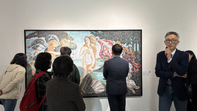 지난달 금정문화회관 금샘미술관에서 개막한 ‘지구 앞에 서다_위태로운 경계에서’ 선보인 크리스 조던의 '비너스'를 자세히 살펴보는 관람객들. 보티첼리의 명화 ‘비너스의 탄생’을 차용한 이 작품은 24만 개의 비닐봉지로 만들어졌다. 사진 오른쪽이 이번 전시 기획을 맡은 석재현 예술감독. 김은영 기자 key66@