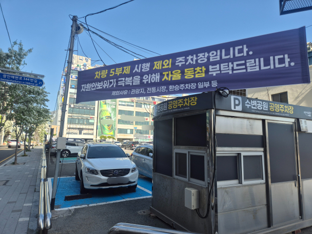 지난 24일 오후 부산 수영구 민락수변공원 인근의 한 공영주차장에 5부제 시행 제외와 함께 자율 동참을 권유하는 현수막이 걸려있다. 김동우 기자 friend@