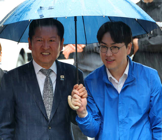 3일 오후 부산 북구 구포시장에서 더불어민주당 정청래 대표와 북갑 국회의원 보궐선거 출마를 공식화한 하정우 전 청와대 AI 미래기획수석이 우산을 쓰고 이동하고 있다. 연합뉴스