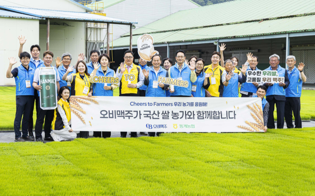 19일 전북 순창군 동계농협에서 열린 ‘국산 쌀 농가 상생 협력 기념행사’를 마치고 동계농협 육묘장에서 단체사진을 찍고 있다. 오비맥주 제공