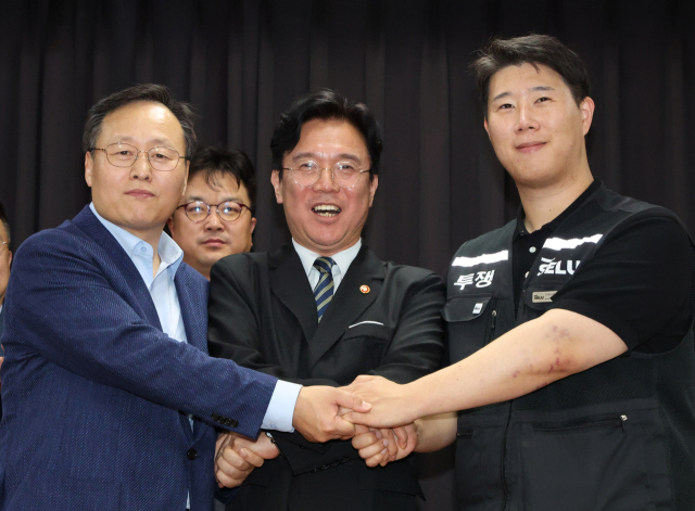 20일 경기도 수원시 장안구 경기고용노동청에서 열린 삼성전자 임금협상을 마친 후 여명구 삼성전자 DS(디바이스솔루션·반도체 사업 담당) 피플팀장과 최승호 삼성그룹 초기업노동조합 삼성전자지부 위원장이 잠정 합의안에 서명한 후 김영환 고용노동부 장관과 손을 맞잡고 있다. 연합뉴스