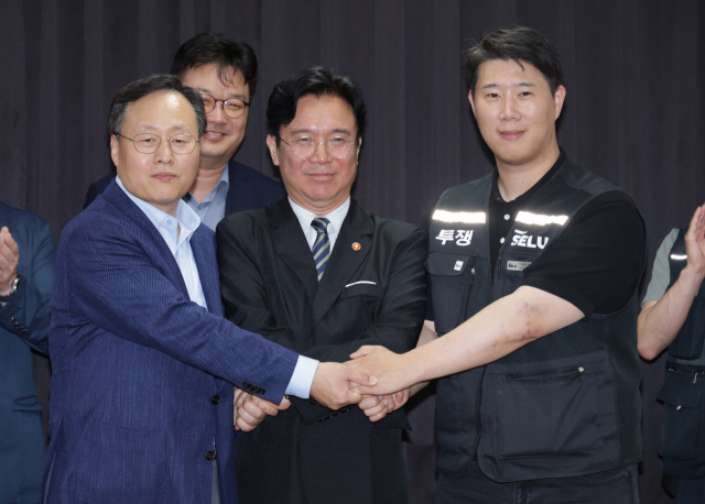 20일 경기도 수원시 장안구 경기고용노동청에서 열린 삼성전자 임금협상을 마친 후 여명구 삼성전자 DS(디바이스솔루션·반도체 사업 담당) 피플팀장과 최승호 삼성그룹 초기업노동조합 삼성전자지부 위원장이 잠정 합의안에 서명한 후 김영환 고용노동부 장관과 손을 맞잡고 있다. 연합뉴스