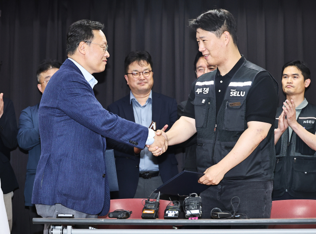 20일 경기도 수원시 장안구 경기고용노동청에서 열린 삼성전자 임금협상을 마친 후 여명구 삼성전자 DS(디바이스솔루션·반도체 사업 담당) 피플팀장과 최승호 삼성그룹 초기업노동조합 삼성전자지부 위원장이 잠정 합의안에 서명한 후 악수하고 있다. 연합뉴스