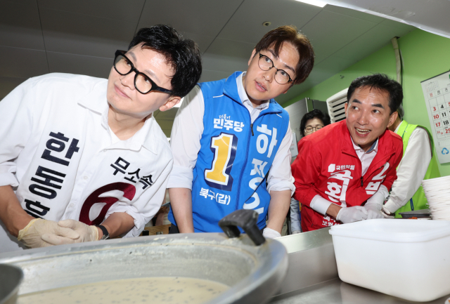 무소속 한동훈(왼쪽부터), 더불어민주당 하정우, 국민의힘 박민식 부산 북구갑 국회의원 보궐선거 후보가 21일 부산 북구 남산정종합사회복지관에서 열린 콩국수 나눔 행사에 참석해 배식 봉사를 하고 있다. 연합뉴스