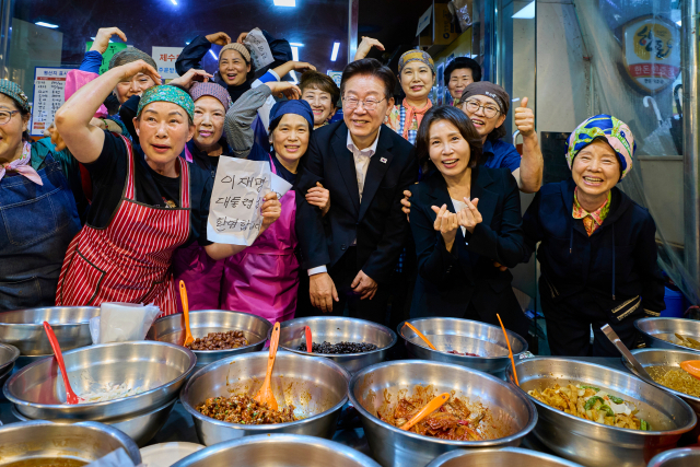 이재명 대통령과 김혜경 여사가 23일 경남 김해 외동전통시장을 방문해 상인 및 시민들과 기념촬영을 하고 있다. 연합뉴스
