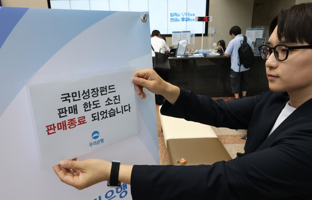 국민참여성장펀드 가입 첫 날인 22일 서울 중구 우리은행 본점 영업점에서 한 직원이 한도소진으로 인한 판매종료 안내문을 붙이고 있다.연합뉴스