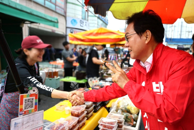 24일 창원 마산합포구 신마산 번개시장을 찾은 국민의힘 박완수 경남지사 후보가 도민과 악수를 나누고 있다. 국민의힘 제공