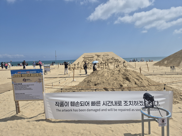 지난 21일 오후 부산 해운대구 해운대해수욕장에서 해운대 모래축제에 출품된 모래 조각 작품이 70대 남성에 의해 훼손됐다. 사진은 작품이 철거된 이후 지난 22일 오후 해운대해수욕장 전시장에 훼손을 알리는 현수막이 걸린 모습. 김동우 기자 friend@