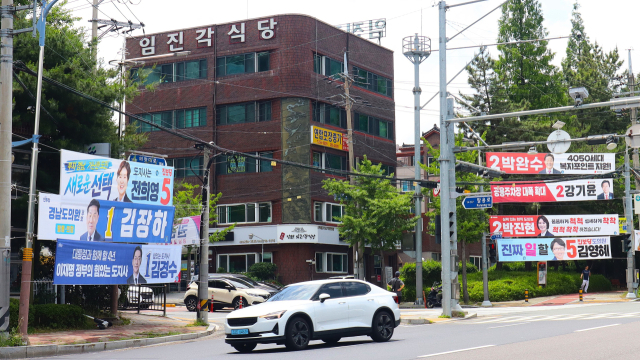 25일 경남 창원시 의창구 서상동 의창사거리에 6·3 전국동시지방선거에 출마한 여야 후보자 현수막이 게시됐다. 더불어민주당 후보는 정부·여당을, 국민의힘은 정책을 강조해 대비되는 모습이다. 최환석 기자