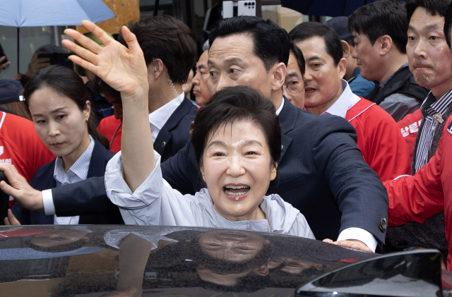 박근혜 전 대통령이 27일 경남 진주시 진주중앙시장을 둘러본 후 차에 오르면서 손 인사하고 있다. 박 전 대통령은 이날 국민의힘 박완수 경남지사 후보, 같은 당 한경호 진주시장 후보 등을 지지하기 위해 진주를 방문했다. 연합뉴스