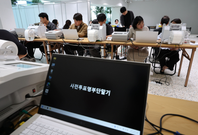 제9회 전국동시지방선거 사전투표를 하루 앞둔 28일 인천국제공항에 설치된 사전투표소에서 선관위 관계자가 기표소와 투표용지 발급기 등 장비를 설치하고 있다. 연합뉴스