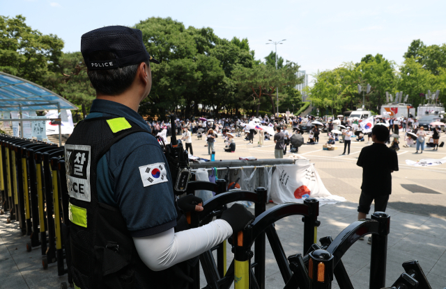 6·3 지방선거 투표용지 부족 사태를 규탄하며 재선거를 요구하는 '잠실 개표소 봉쇄 시위'가 계속되고 있는 9일 서울 송파구 올림픽공원 핸드볼경기장 출입구 앞에서 한 경찰이 집회를 지켜보고 있다. 연합뉴스