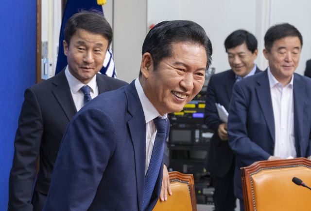 더불어민주당 정청래 대표가 17일 국회에서 열린 최고위원회의에 입장해 물건을 책상에 떨어뜨린 한정애 정책위의장을 미소 지으며 바라보고 있다. 연합뉴스