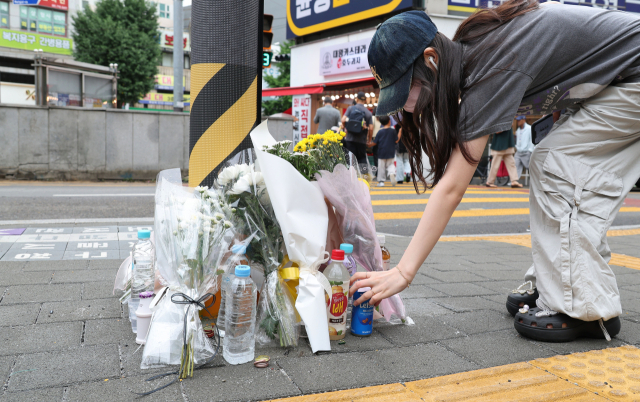 지난 21일 오후 부산 남구 대연동의 한 도로에서 70대 남성이 몰던 승용차가 인도를 덮쳐 행인 2명이 숨지고 2명이 다치는 사고가 발생했다. 22일 한 시민이 사고 현장에 고인을 추모하는 꽃과 음료수를 내려놓고 있다. 정종회 기자 jjh@
