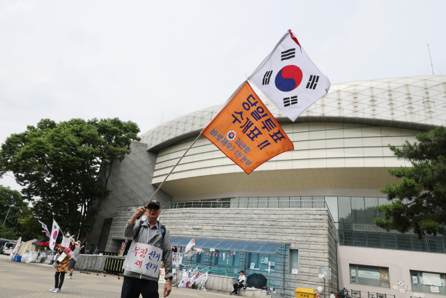 22일 6·3 지방선거 잠실 개표소로 사용된 서울 송파구 올림픽공원 핸드볼경기장 앞에서 6·3 지방선거 투표용지 부족 사태 규탄 봉쇄 시위 참가자들이 재선거 및 당일투표 수개표 촉구 구호를 외치고 있다. 연합뉴스